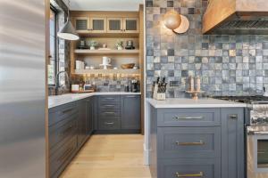 a kitchen with blue cabinets and a tile wall at 11981 N Gemini Way SkyRidge 5BR Home with Hot Tub home in Keetley