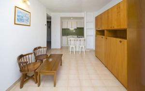 Apartamentos Cala LLonga Playa في كالا يونغا: مطبخ وغرفة معيشة مع طاولة وكراسي