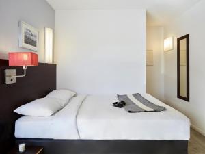 a bedroom with two white beds and a red lamp at Aparthotel Adagio Access Paris Bastille in Paris