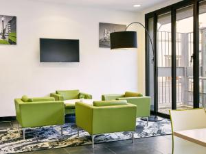 una sala de espera con sillas verdes y TV en Aparthotel Adagio Access Paris Bastille, en París
