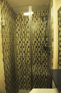 ein Bad mit einer Dusche mit schwarzen und braunen Fliesen in der Unterkunft Little House in Neapel
