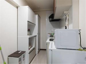 a small white kitchen with a microwave on a counter at House L in Shinjuku in Tokyo