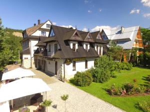 uma grande casa branca com um telhado em Gościniec i Herbaciarnia Pod Złotą Łyżwą em Białka Tatrzanska