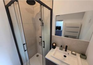 a bathroom with a sink and a shower with a mirror at Maisonnette familiale entre Nantes et Pornic in Brains