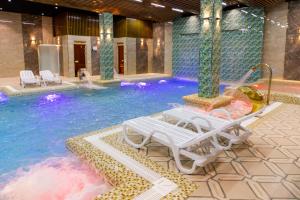 a swimming pool with a chaise lounge chairs in a hotel at Karvon Plaza Hotel in Samarkand