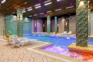 a pool with chaise lounges and chairs in a hotel at Karvon Plaza Hotel in Samarkand