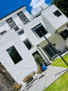 a white building with chairs in front of it at Casa Veta Corona Tlalpujahua in Tlalpujahua de Rayón