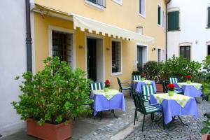 a patio with blue tables and chairs with flowers at Charming Hotel dei Chiostri in Follina