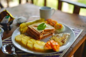 a plate of food with bread and fruit on a table at The Mirror Wall Sigiriya in Sigiriya