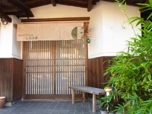 un banco de madera sentado frente a una puerta en Guesthouse Shirahama, en Shirahama