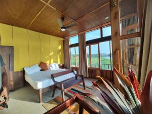 a bedroom with a bed and a chair and windows at Kyna Backwater Resort Alleppey Alappuzha in Alleppey