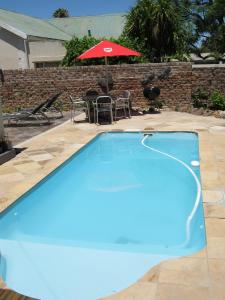 a blue swimming pool with a table and an umbrella at Ladismith Manor in Ladismith