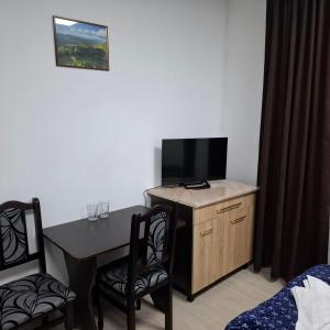 a room with a desk with a tv and a table and chairs at Готель Верховинський in Sushitsya