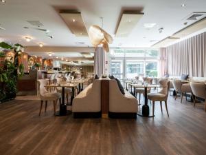 a restaurant with tables and chairs and a lamp at Mercure Paris Ouest Saint Germain in Saint-Germain-en-Laye