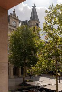 un bâtiment doté d'une tour d'horloge avec des arbres devant lui dans l'établissement Core Luxembourg City - Bullseye, à Luxembourg
