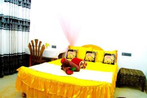 Un dormitorio con una cama amarilla con un osito de peluche. en Golden Eco Ayur Villa, en Dambulla