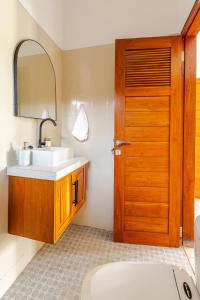 Un baño con lavabo y puerta de madera. en Villa Ulu 2 bedroom, en Uluwatu