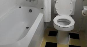 La salle de bains est pourvue de toilettes blanches et d'une baignoire. dans l'établissement Rawanda Resort Hotel, à Ban Khlong Pho