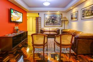 a living room with leather furniture and a television at Hotel Erechim in Porto Alegre