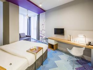 a hotel room with a bed and a desk and a tv at Ibis Styles Lviv Center in Lviv