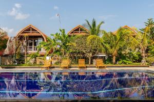 Un grupo de sillas junto a una piscina. en Villa Ulu 2 bedroom, en Uluwatu