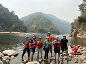 a group of people standing in the water on a river at shnongpdeng tents stay in Dawki