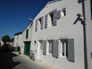 un vélo garé sur le côté d'un bâtiment blanc dans l'établissement Maison Rétaise près de la Plage, à Saint-Clément-des-Baleines