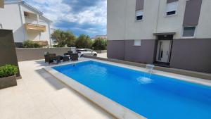 a large blue swimming pool in front of a building at The Sands LUXE Pool Aparthotel, Studio in Novalja +3 photos
