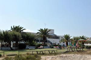 un parque con palmeras y gente sentada en la playa en Hotel Il Timone en Specchiolla 