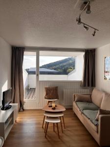 a living room with a couch and a large window at Le nid du Buron - Super-Besse in Besse-et-Saint-Anastaise +3 photos