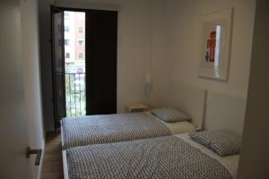 two twin beds in a room with a window at Apartamentos Hiedra y Tapinería Mercado Central in Valencia