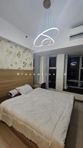 a bedroom with a large bed and a chandelier at Apart Anderson in Surabaya
