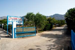 a blue gate with a sign next to a road at Dolphin Apartments in Frangokastello