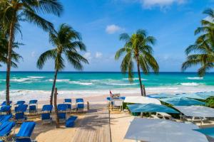 a beach with chairs and palm trees and the ocean at Turtle Beach, a Tribute Portfolio All Inclusive Hotel in Christ Church