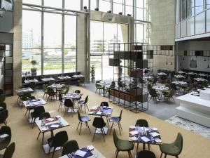 a dining room with tables and chairs and windows at Ibis Styles Dubai Jumeira in Dubai