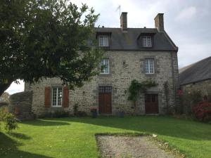 een oud stenen huis met een groene tuin bij L'ancien Presbytère d'Ardevon in Ardevon