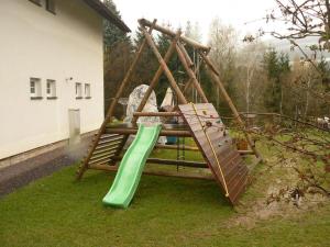 a playground with a green slide in a yard at Apartman Janky 299 in Trutnov