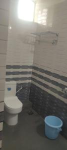 a bathroom with a toilet and a blue bucket at Calangute Pristine Guest House in Calangute