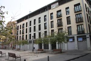 a large white building with benches in front of it at Apartamentos Hiedra y Tapinería Mercado Central in Valencia