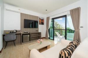 a living room with a couch and a tv at The Hideout Beachfront in Patong Beach