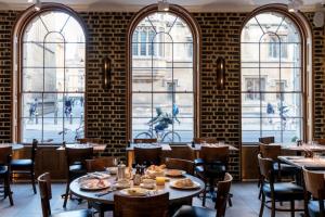 un restaurante con mesas, sillas y ventanas en Old Bank Hotel en Oxford