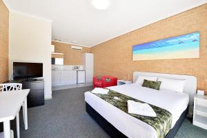 a bedroom with a large bed and a kitchen at Cranbourne Motor Inn in Cranbourne