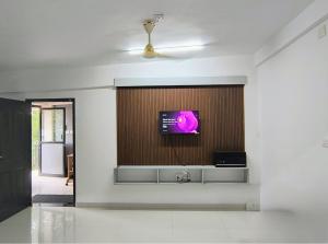 Una sala de estar con un televisor en la pared. en Harmony Residence, en Trivandrum