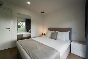 a bedroom with a large white bed and a mirror at Welcome Douro - Eco Camping Resort in Cinfães +85 photos