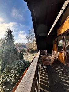 a wooden deck with two chairs on a house at Lütt Heidjer Hus in Buchholz in der Nordheide