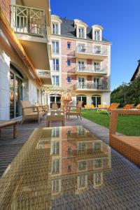 a building with a reflection of a table and benches at La Closerie SPA & Résidence Hôtel in Deauville