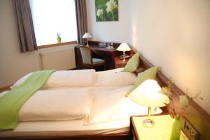 a bedroom with a bed and a desk with a lamp at Altstadt Hotel Meppen in Meppen