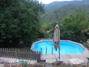 a swimming pool with an umbrella next to it at Gîte du BONELLI in Malarce-sur-la-Thines