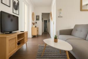 Una sala de estar con un sofá y un televisor. en IDÉAL Pro & Familles, Au Calme, Tout Confort, Netflix et Disney Plus, en Saint-Étienne
