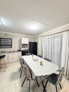 a dining room with a white table and chairs at Zambezi luxe stay in Pretoria +12 photos